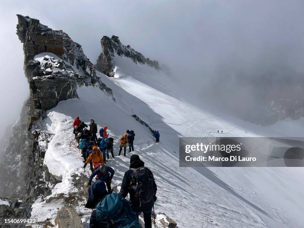 Hikers walk to reach the summit of Monte Gran Paradiso at an altitude of 4061 meters above sea level in the mountains of the Gran Paradiso National...