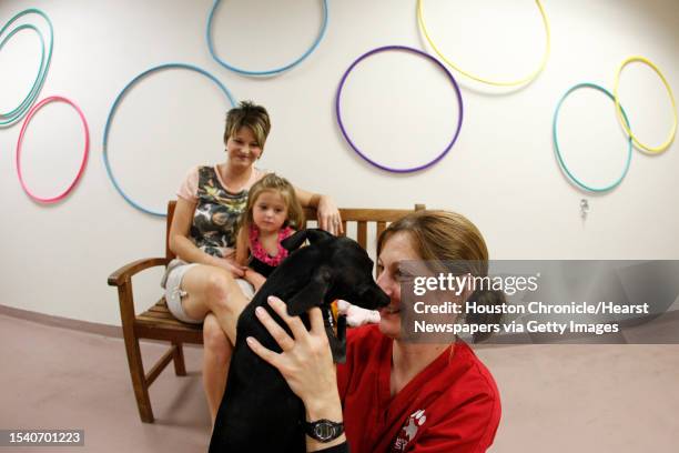 Maggie Kovacs, a veterinarian technician, says hello to Doxi, a dachshund Chihuahua mix who was born without front legs, as Doxi visits the Houston...