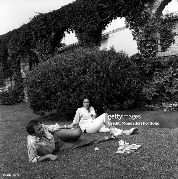 The singer Domenico Modugno relaxes with his wife, the actress Franca Gandolfi, in the garden. Lying on the grass beside them a pack of cigarettes...