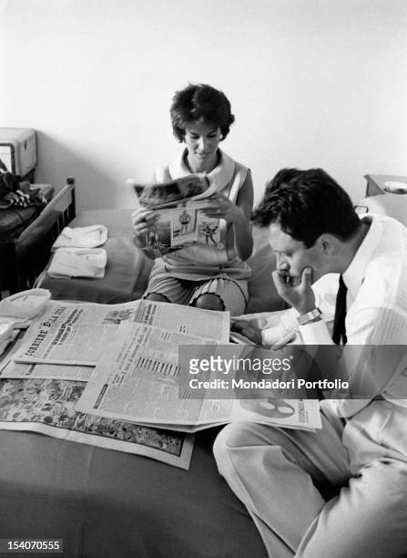 Italian actors Franco Interlenghi and Antonella Lualdi reading the newspaper in their bedroom. Venice, 26th August 1958