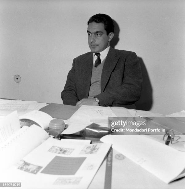 Italo Calvino, italian writer and Einaudi publishing company's associate, sits at his desk filled with paperwork. Turin , July 1959.