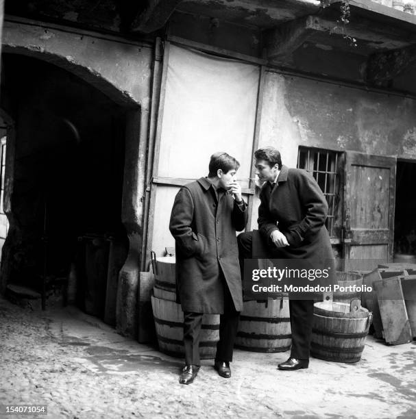 The Italian actor of cinema, theatre and tv Corrado Pani and the US actor Joseph Walsh are chatting in the inner courtyard of a modest house; Pani is...