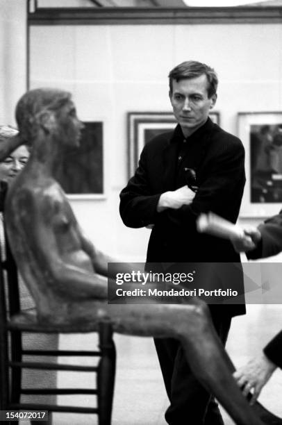Russian writer Yevgeny Yevtushenko watching the sculpture Ragazza Seduta by Giacomo Manz? at GAM. Turin, 1960s