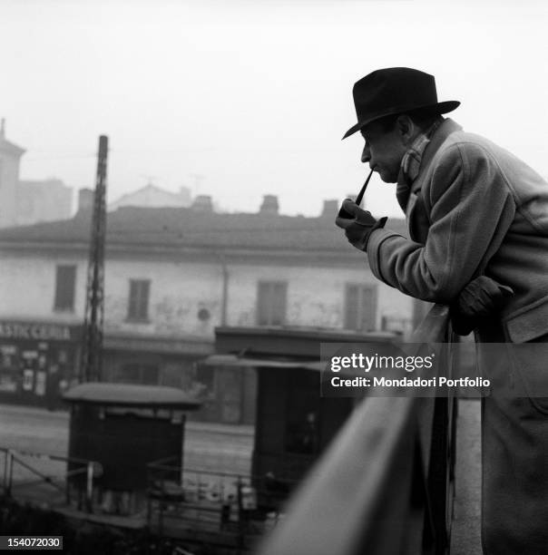 Belgian writer Georges Simenon smoking the pipe on a bridge. Milan, 1950s