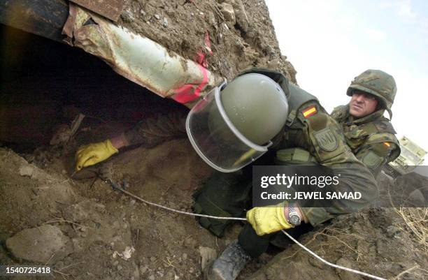 Sargent Gelo , a Spainsh soldier from a special demining group, is watched by Captain Alejandre as he cleans soil off unexploded grenade found at the...