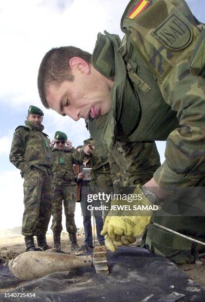 Sargent Gelo , a Spainsh soldier from a special demining group, is watched by colleagues as he checks an unexplosed grenade found at the...