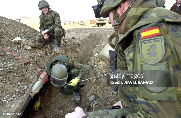 Sergeant Gelo , a Spainsh soldier from a special demining group, is watched by his colleagues as he moves soil to remove an unexplosed grenade found...