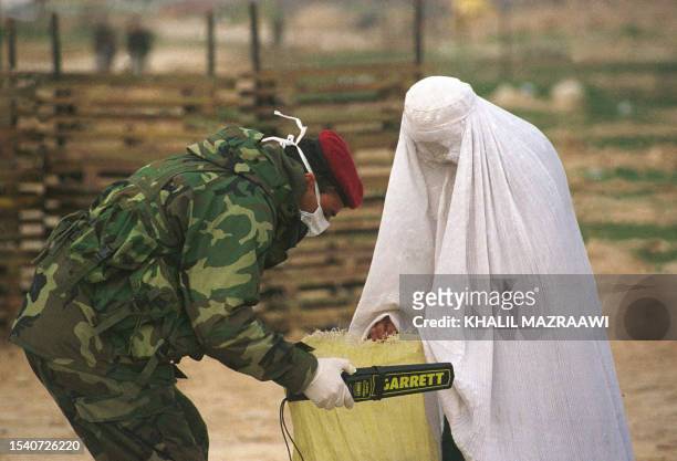 Jordanian soldier checks the bag of an Afghan woman visiting a sick relative 16 February 2002 at the Jordanian army's field hospital in...