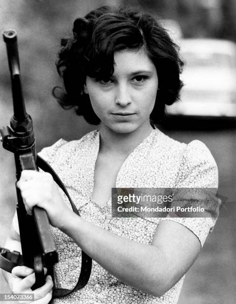 The Italian actress Lina Polito posing with a machine gun in her hands during a break in the film Salvo D'Acquisto. Rome, 1975