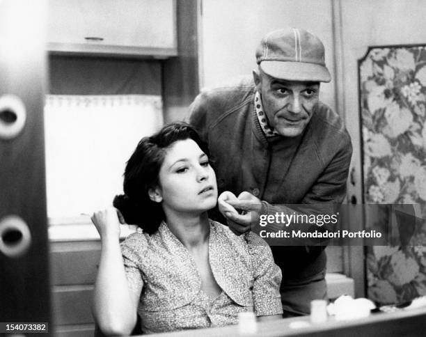 Make-up man putting foundation cream on the face of the Italian actress Lina Polito on the set of the film Salvo D'Acquisto. Rome, 1975