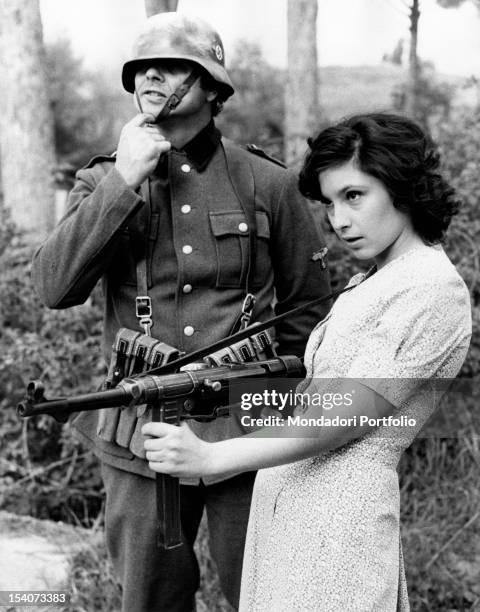 The Italian actress Lina Polito pretending to shoot with a machine gun during a break in the film Salvo D'Acquisto. Rome, 1975