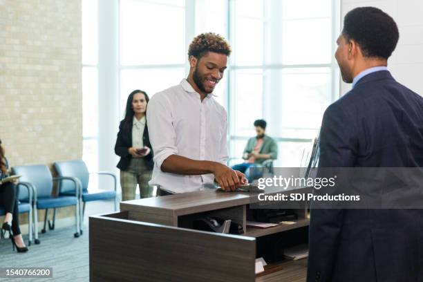 smiling young man withdraws cash from account at bank - bankpersoneel stockfoto's en -beelden