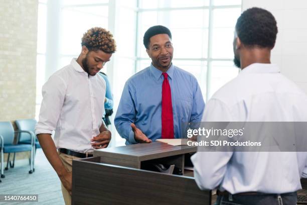 businessman and young adult son talk to bank manager - finance talk stockfoto's en -beelden