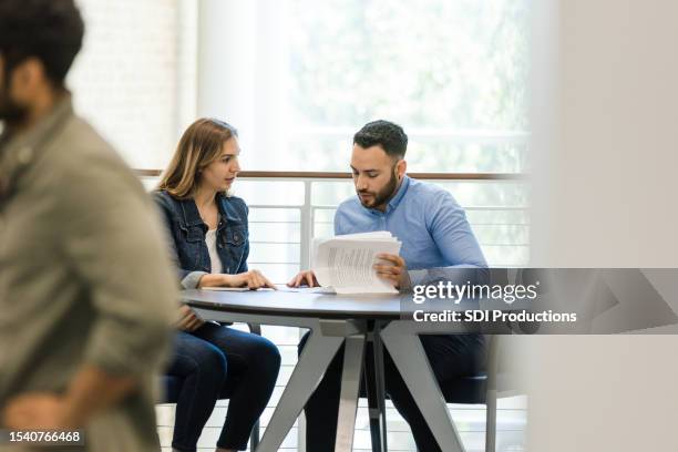 frau im mittleren erwachsenenalter und junger erwachsener mann diskutieren arbeitsberichte - bankberater stock-fotos und bilder