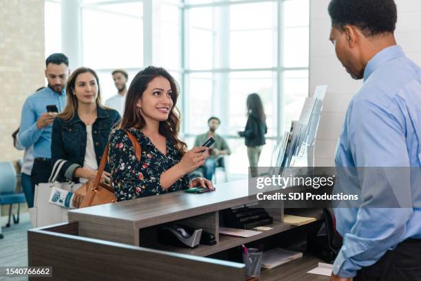 unterschiedliche menschen warten geduldig, als frau dem kassierer eine karte gibt - bank teller and customer stock-fotos und bilder