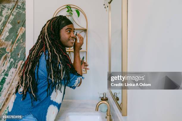 bipoc trans woman applying makeup in bathroom - standing mirror stock pictures, royalty-free photos & images