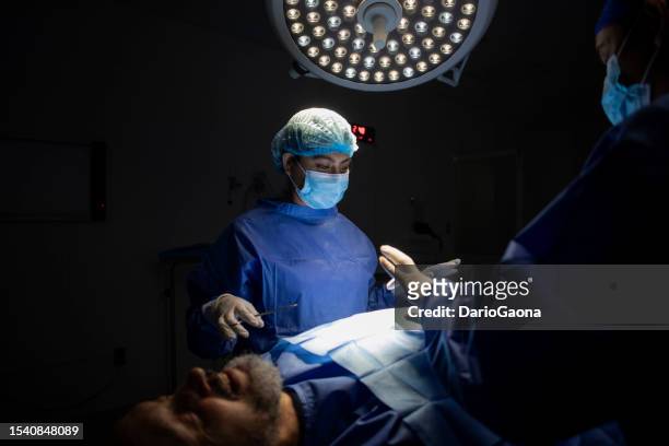 doctors in surgery in the operating room - diversidad 個照片及圖片檔