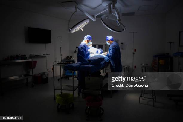 doctors in surgery in the operating room - gente común y corriente stock pictures, royalty-free photos & images