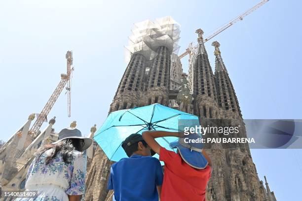 Children use an umbrella as they look at the Sagrada Familia basilica in Barcelona on July 18, 2023. Spain issued hot weather red alerts for three...