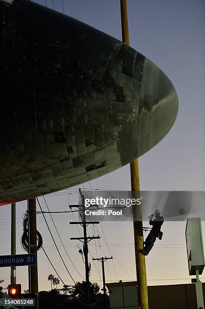 Man climbs a pole to take a picture of Space Shuttle Endeavour on Crenshaw Blvd. Enroute to the California Science Center during its final journey on...