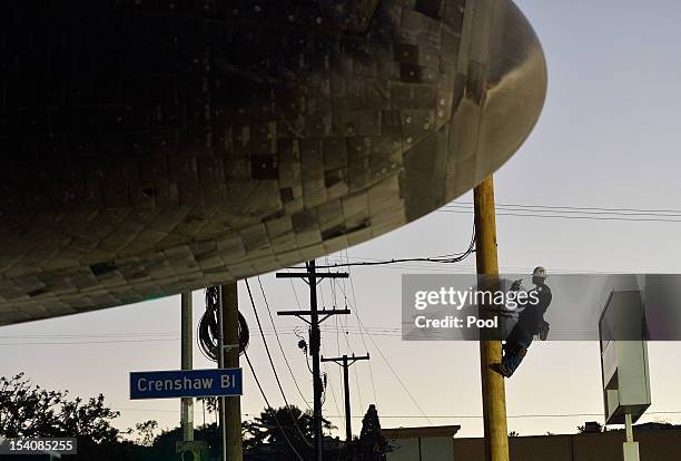 Man climbs a pole to take a picture of Space Shuttle Endeavour on Crenshaw Blvd. Enroute to the California Science Center during its final journey on...