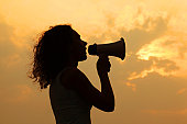 Woman holding megaphone and shouted into it at sunset