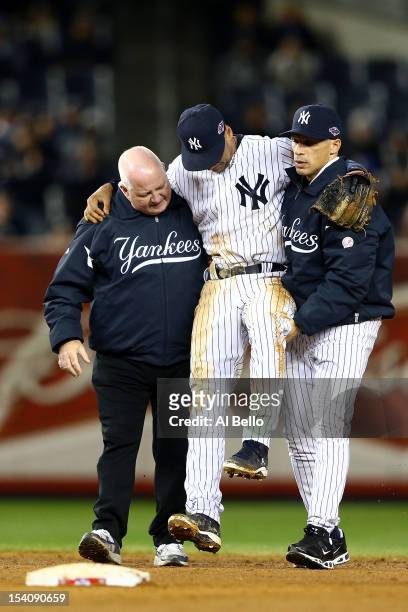 Derek Jeter of the New York Yankees is carried off of the field by trainer Steve Donohue and manager Joe Girardi after Jeter injured his leg in the...