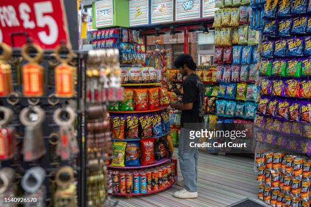 Worker adjusts the display in an American-style candy shop on Oxford Street on July 18, 2023 in London, England. The proliferation of American-style...