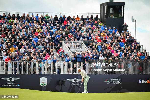 Rory McIlroy of Northern Ireland putts on the 18th hole green as fans look on from the grandstand during the final round of the Genesis Scottish Open...