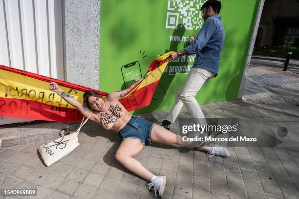 An activist of feminist group FEMEN with her bare chest painted with messages against gender-based murder of women is dragged during a protest in...