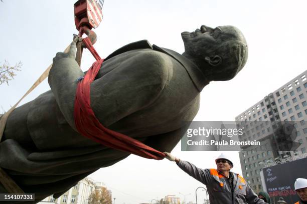Mongolian worker holds onto the hiost as the famous statue of the Vladimir Lenin is taken down by crane and placed on a truck for removal after many...