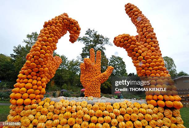 People walk past a sculpture of three hands made of pumpkins symbolizing the Swiss "Ruetli oath" at a pumpkin exhibit at the Baroque Castle in...