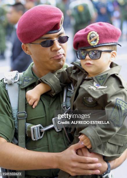 Soldier of the Batallion of Parachuters of the Mexican army, hold his child,who is wearing a military uniform, moments before the commencement of the...