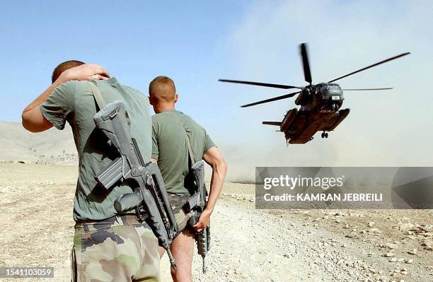 Two French soldiers watch a CH-531 GS helicopter of German contingent International Security Assistance Force in a dust landing training session...