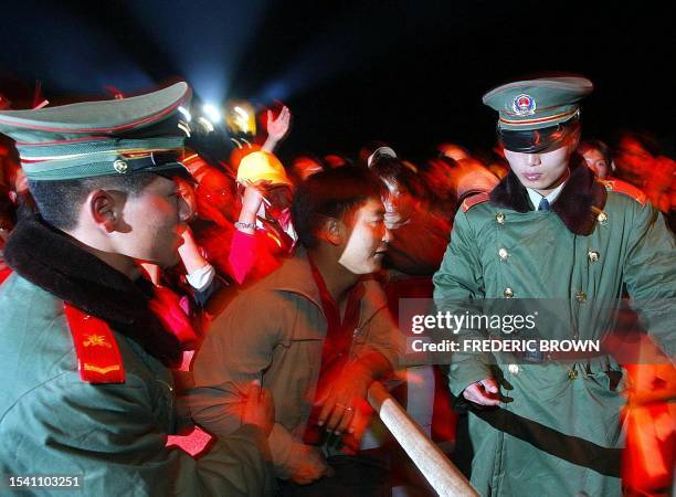 Chinese People's Liberation Army soldiers apprehend a fan for climbing over a barrier at the Snow Mountain Festival in Lijiang, 18 August 2002. This...