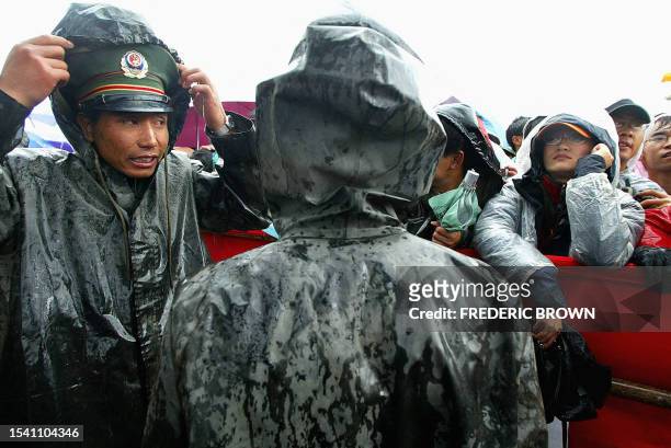 Soldier takes cover from the rain, 17 August 2002, at the Snow Mountain Festival in Lijiang, southwestern Yunnan province. Despite the persistent...