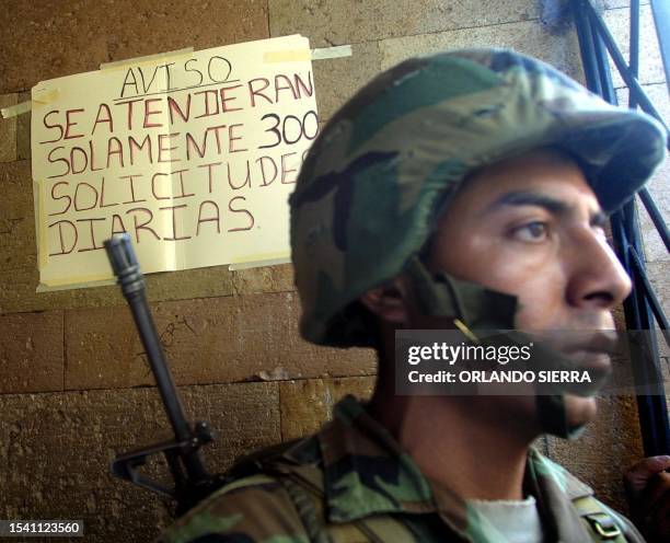 Soldier of the Honduran Military stands guard outside of the Passport Office in Tegucigalpa, where hundreds of citizens stand in line waiting to get...