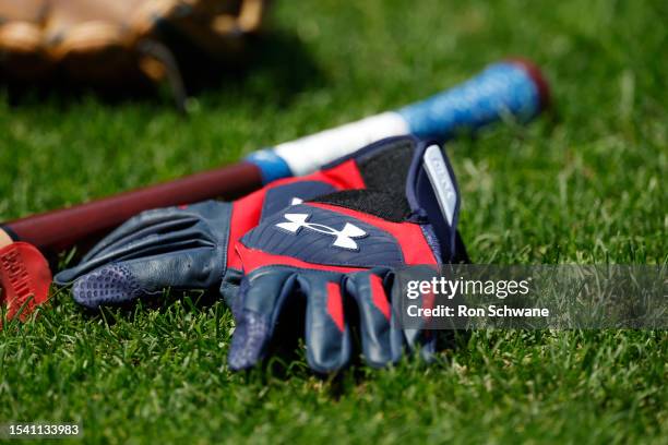 Pair of Under Armour batting gloves and a bat sit on the field at Progressive Field before a game between the Cleveland Guardians and the Kansas City...