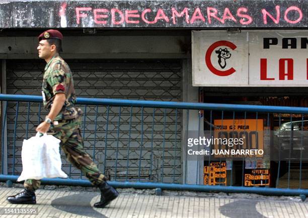 Member of the National Guard walks by graffiti written against the Fedecamaras organization, in Caracas, 09 April 2002. Un miembro de la militarizada...