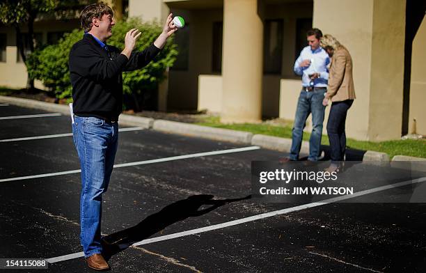 Traveling press secretary Rick Gorka catches a football while playing catch as other staff members go over the schedule while waiting outside the...