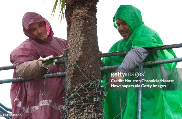 Carlos Calderon, left, and Jose Peralta, both with Always in Season holiday decorating company brave eight hours of rain as they remove Christmas...