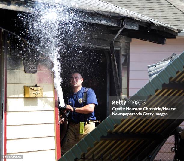 Captain Michael Rodriguez, of Station 29, hits a smouldering piece of wood with water as he mops up a fire, Monday, Aug. 22 at the 900 block of Toni...