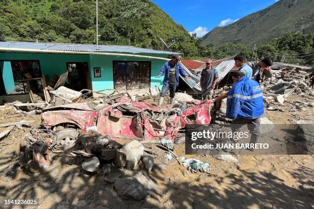 People stand next to a destroyed car after a landslide in the Quetame municipality, Cundinamarca department, Colombia, on July 18, 2023. Rescue teams...