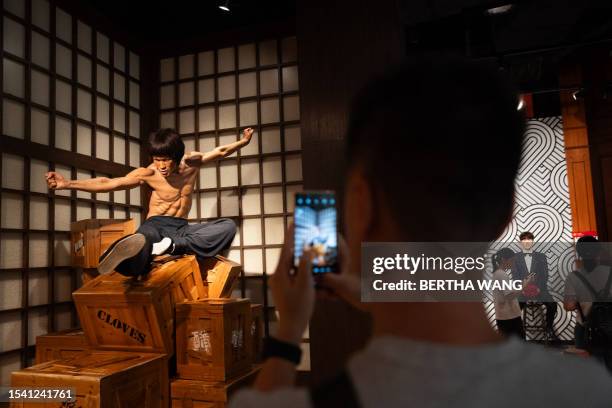 In this photo taken on July 18, 2023 a visitor takes a photo of the wax figure of Bruce Lee at the Madame Tussauds wax museum in Hong Kong, ahead of...