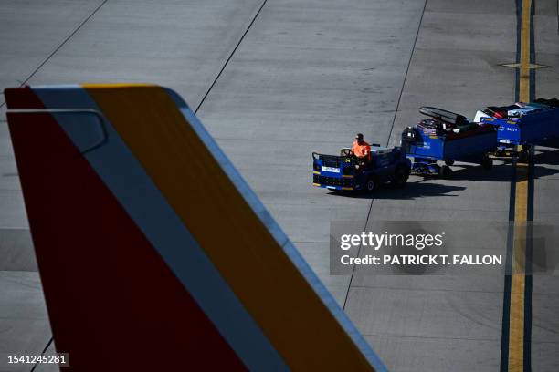 Southwest Airlines ground worker drives a baggage cart along the tarmac at Phoenix Sky Harbor International Airport during a record heat wave in...