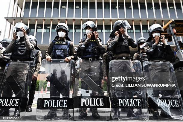 Police in riot gear line up behind the gates of the Thai Parliament as protesters gather following the suspension of leader and prime minister...