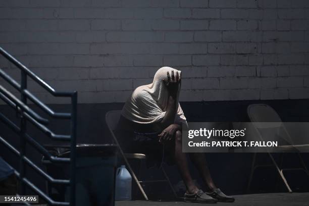 Person covers their head while trying to stay cool in "The Zone," a vast homeless encampment where hundreds of people reside, during a record heat...