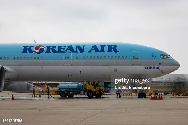 Airport workers clean a Boeing Co. 777-300ER passenger aircraft, operated by Korean Air Lines Co., on the tarmac outside the company's hangar at...