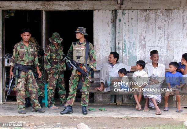 Indonesian troops take a rest as villagers look on in the Nisam subdistrict in North Aceh, 20 November 2002. Exiled leaders of the Aceh separatist...