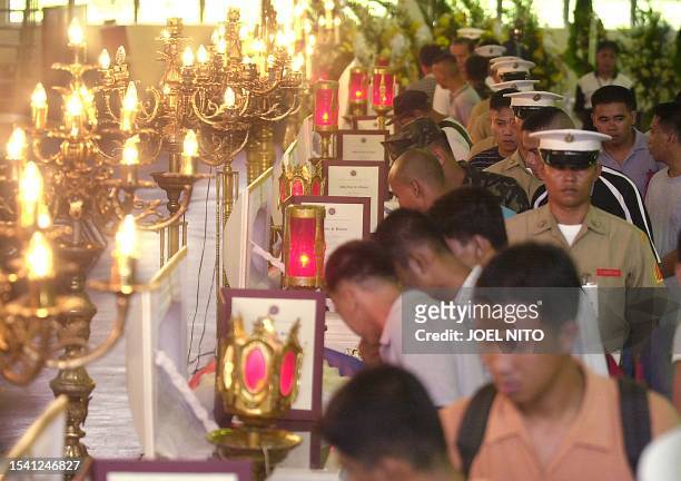 Relatives and friends pay their last respects 16 October 2002 at the Philippine Marine headquarters in Manila over flag-draped coffins of 11 Marines...